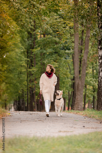 A woman walks with her labrador in the fall.