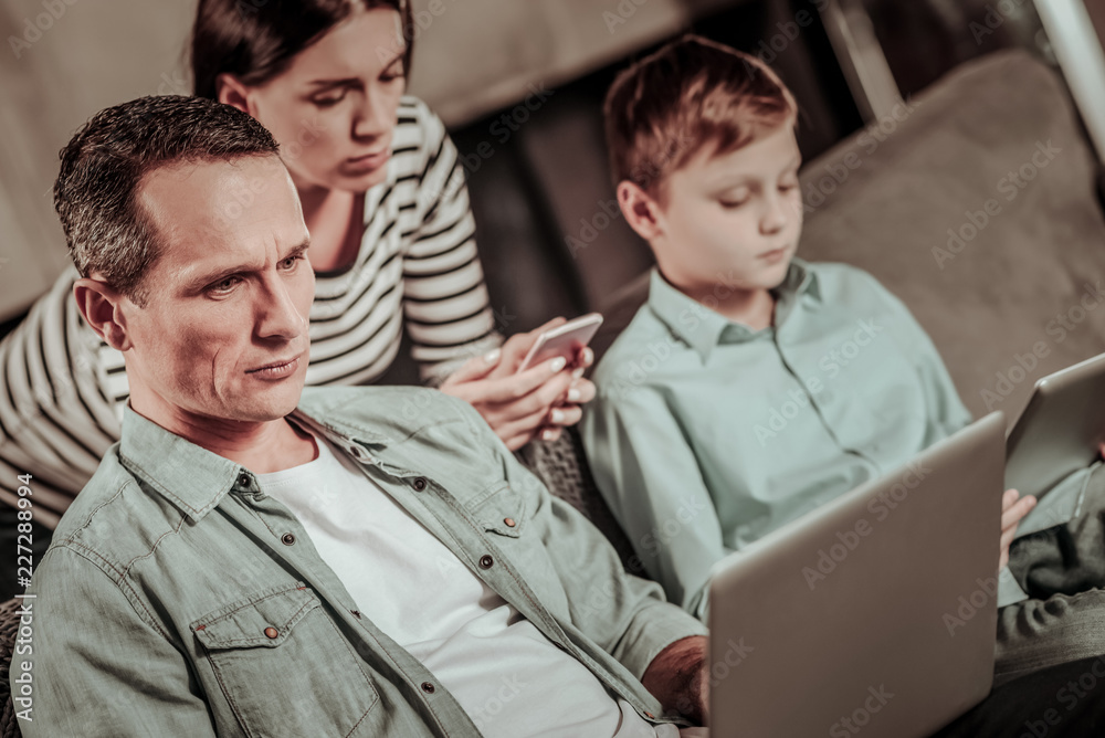 Let me think. Attentive man wrinkling forehead while looking at his gadget Let me think. Attentive man wrinkling forehead while looking at his gadget