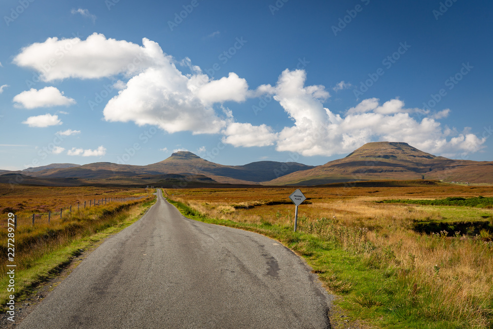 Empty single track road leading towards hills in scenic landscape, Isle of Skye, Scotland