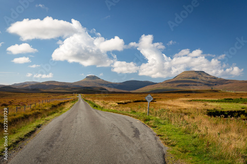 Empty single track road leading towards hills in scenic landscape, Isle of Skye, Scotland