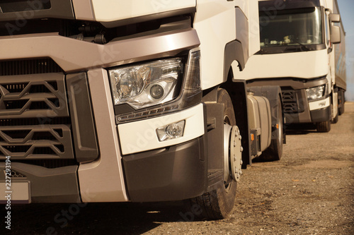 Detail view of the front part of 18 wheeled trucks in the background of the second truck. photo