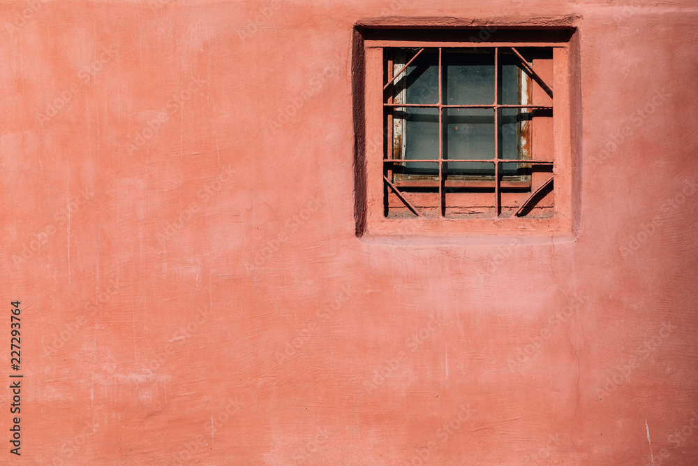 Fototapeta premium red wall with a small glass window and bars