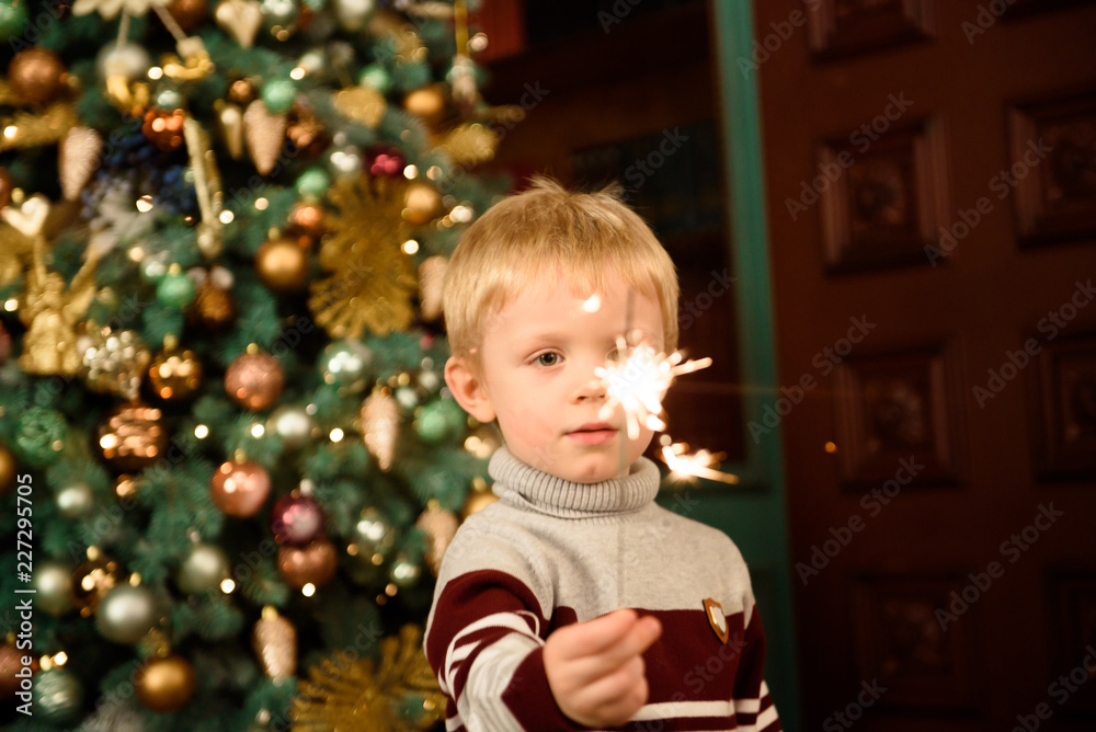Happy family mother and son with sparkler near a Christmas tree