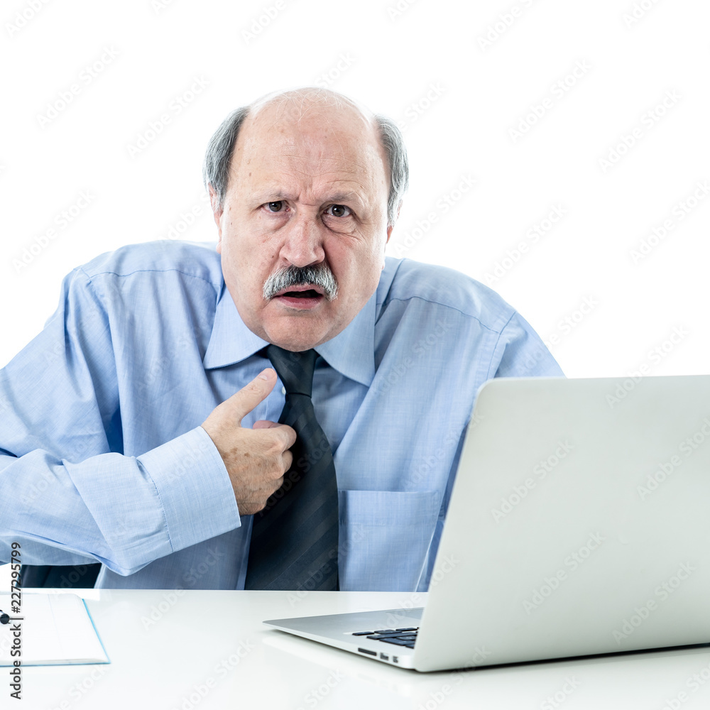 Overwhelmed and tired old businessman working with laptop feeling angry at office Overwhelmed and tired old businessman working with laptop feeling angry at office