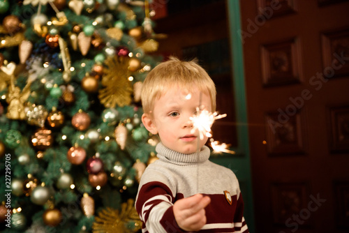 Happy family mother and son with sparkler near a Christmas tree