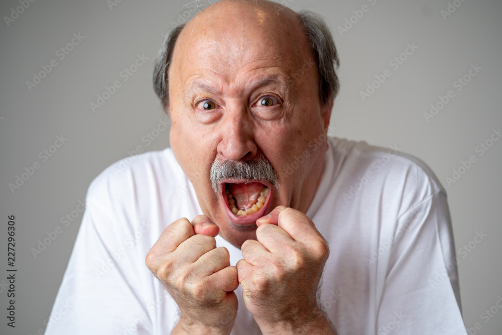 Close up of scared and shocked senior man gesturing in fear with hands and face Close up of scared and shocked senior man gesturing in fear with hands and face