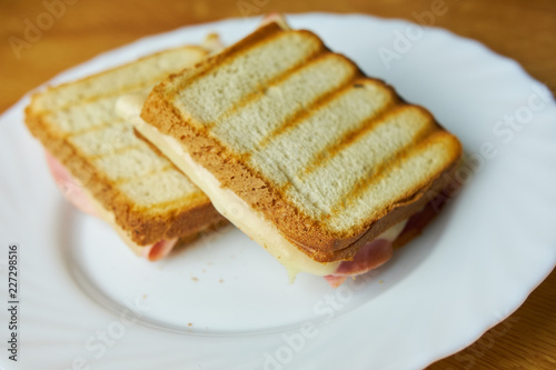 Tasty ham and cheese toast on white plate