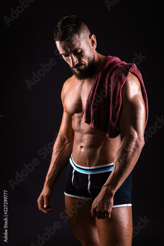 Muscular man is showing his torso with towel on the shoulders