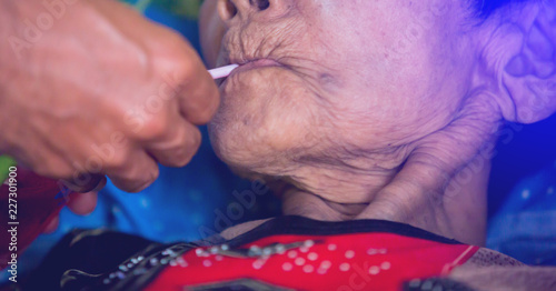 Fotografie Old woman is sucking water from a tube.