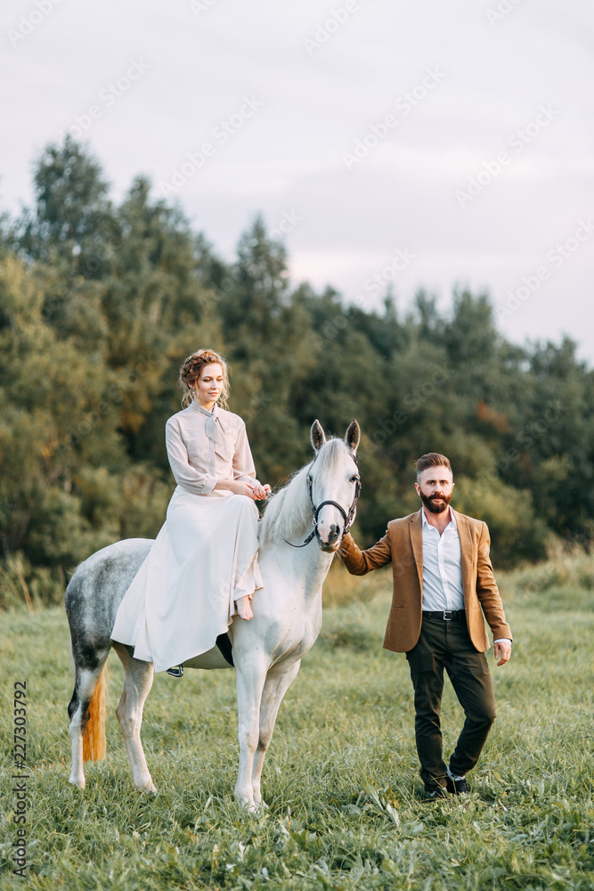 Obraz premium Wedding in American style, on a ranch with a horse. Walk couples in the fields at sunset, with friends and on horseback. Modern couple and ideas for the ceremony.