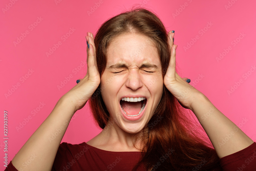 don't want to hear it. rejection refusal and denial. young woman covering ears with hands. portrait of a screaming girl with tightly shut eyes on blue background. don't want to hear it. rejection refusal and denial. young woman covering ears with hands. portrait of a screaming girl with tightly shut eyes on blue background.