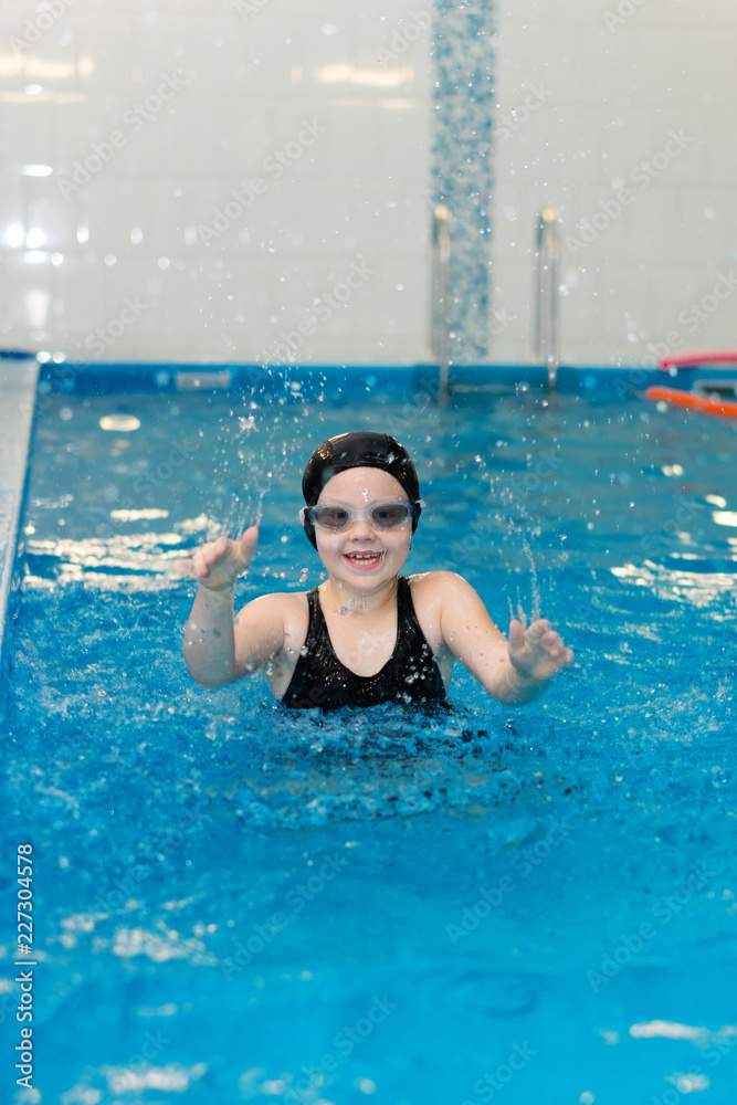 swimming lessons for children in the pool - beautiful fair-skinned girl swims in the water
