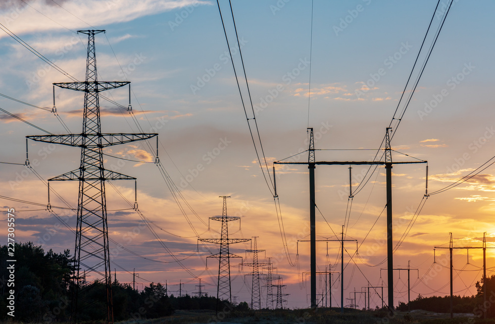 high-voltage lines against the background of electrical distribution stations at sunrise.
