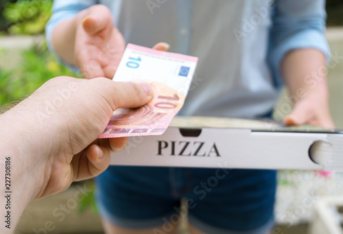 Woman delivering pizza in box and taking payment.