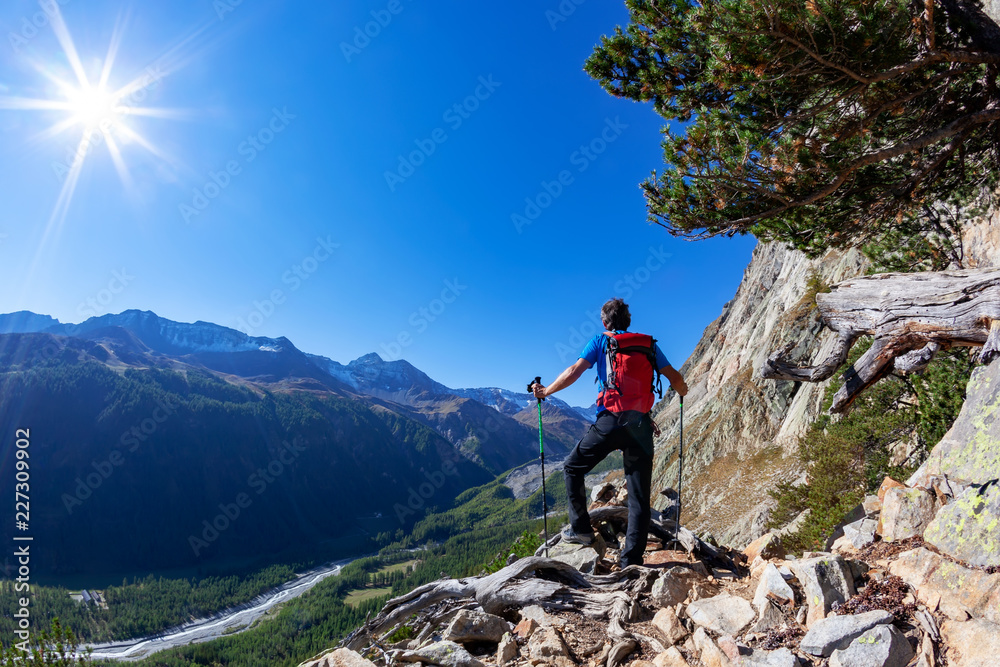 Hiker takes a rest observing a mountain panorama. Mont Blanc Massif, Italian Alps, Val D'Aosta, Italy. Concept: adventure, travel, outdoor.
