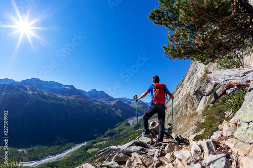 Hiker takes a rest observing a mountain panorama. Mont Blanc Massif, Italian Alps, Val D'Aosta, Italy. Concept: adventure, travel, outdoor.