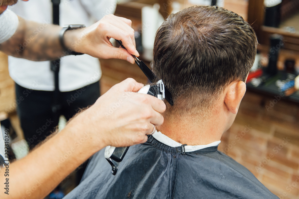 barber cutting hair with scissors. back view of man in barber shop barber cutting hair with scissors. back view of man in barber shop