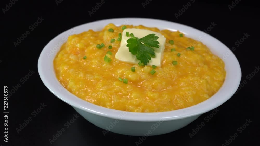 Pumpkin porridge with rice, milk, vanilla and sugar in a plate rotates on a black background. Close up, macro, 4k. Organic food Pumpkin porridge with rice, milk, vanilla and sugar in a plate rotates on a black background. Close up, macro, 4k. Organic food