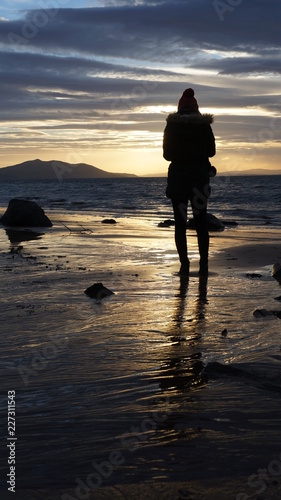 Silhouette of young woman standing looking out at the sea