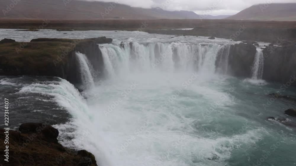Powerful raging whitewater waterfall falling forcefully over a rocky edge. Crystal clear glacier water stream dropping over the cliff Powerful raging whitewater waterfall falling forcefully over a rocky edge. Crystal clear glacier water stream dropping over the cliff
