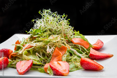 Strawberry, avocado, lettuce salad with cashew nuts on plate