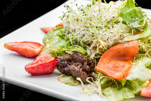 Strawberry, avocado, lettuce salad with cashew nuts on plate photo