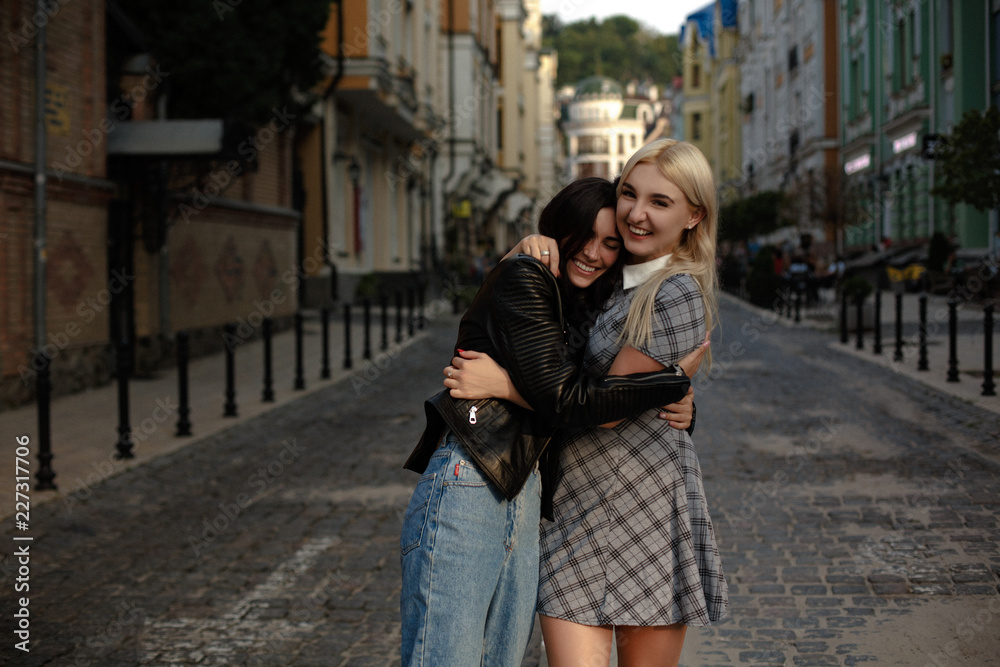 Lesbian couple walking in the city. Hugging and smiling. Standing on the pavement.