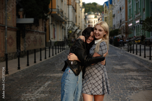 Lesbian couple walking in the city. Hugging and smiling. Standing on the pavement.