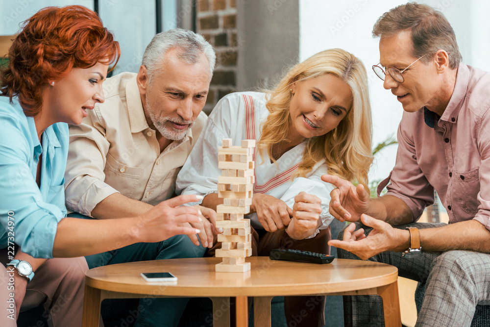 two mature couples playing with wooden blocks at home two mature couples playing with wooden blocks at home