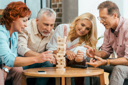 two mature couples playing with wooden blocks at home