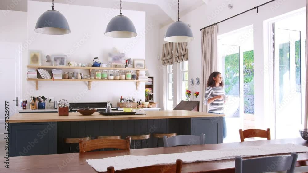 Mixed race woman drinking coffee in open plan kitchen