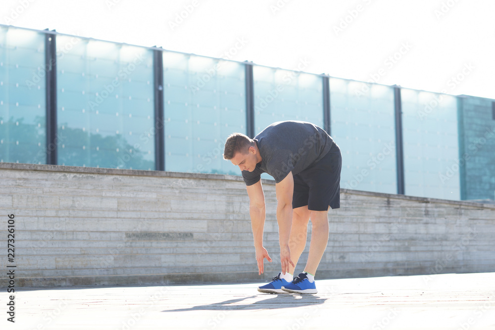 Young and sporty man training outdoor in sportswear. Sport, health, athletics.