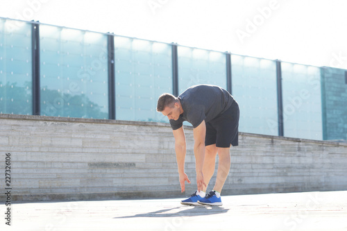 Young and sporty man training outdoor in sportswear. Sport, health, athletics.