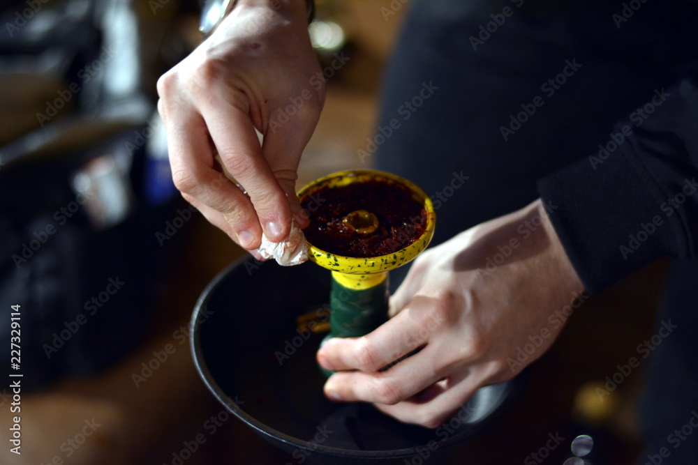 a man prepares a hookah, puts tobacco