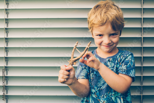 Blonde boy playing with a slingshot