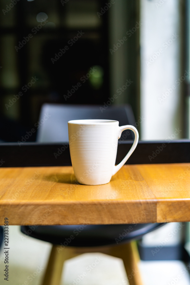 White coffee or tea mug on a desk at an office White coffee or tea mug on a desk at an office