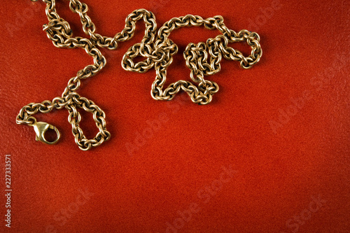 Gold chain on reddish brown leather background.