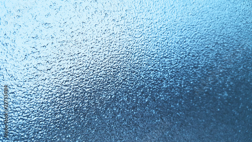 Frozen winter glass or window, abstract blue background.