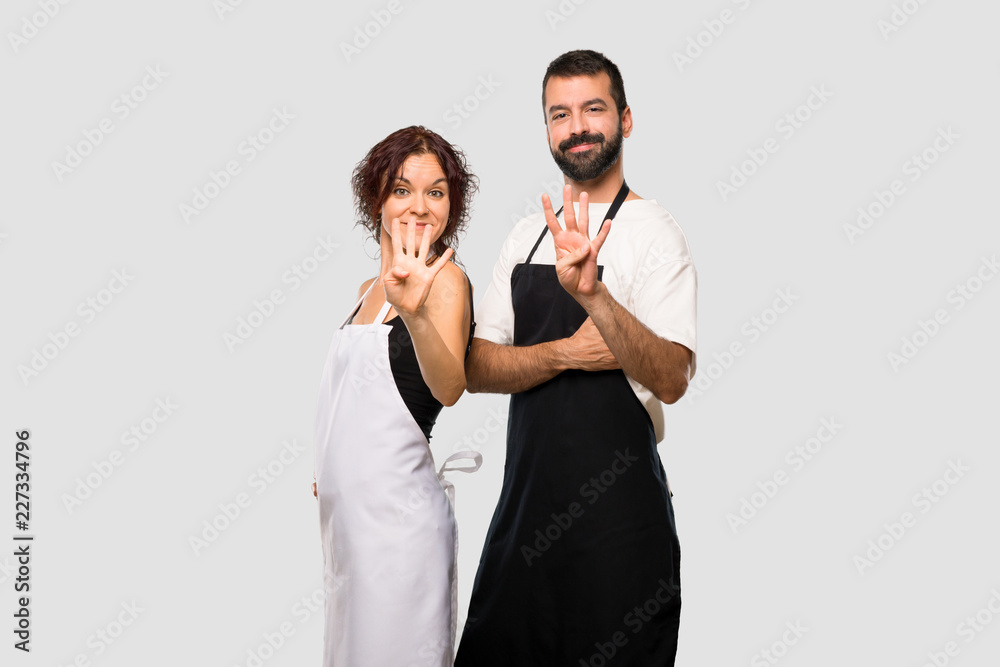 Couple of cooks happy and counting four with fingers on grey background Couple of cooks happy and counting four with fingers on grey background