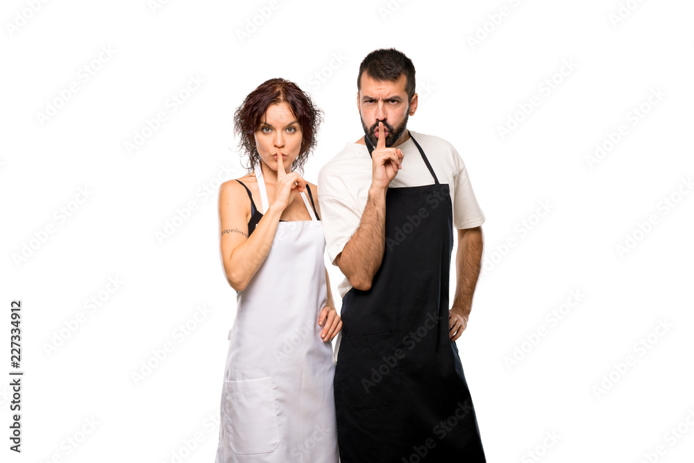 Couple of cooks showing a sign of silence gesture putting finger on isolated white background Couple of cooks showing a sign of silence gesture putting finger on isolated white background