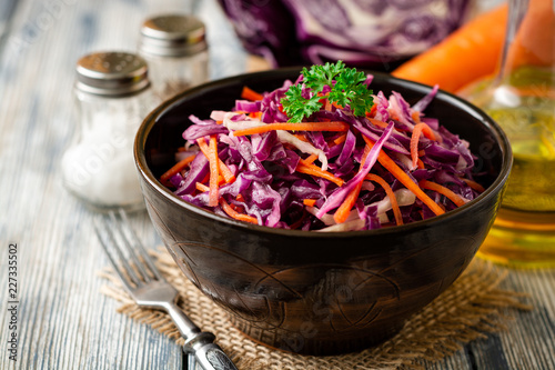 Fresh coleslaw salad with red and white cabbage and carrots in bowl on vintage wooden background. Selective focus. photo