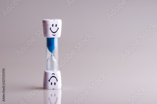 Hourglass on a white background. Blue sand. Smile