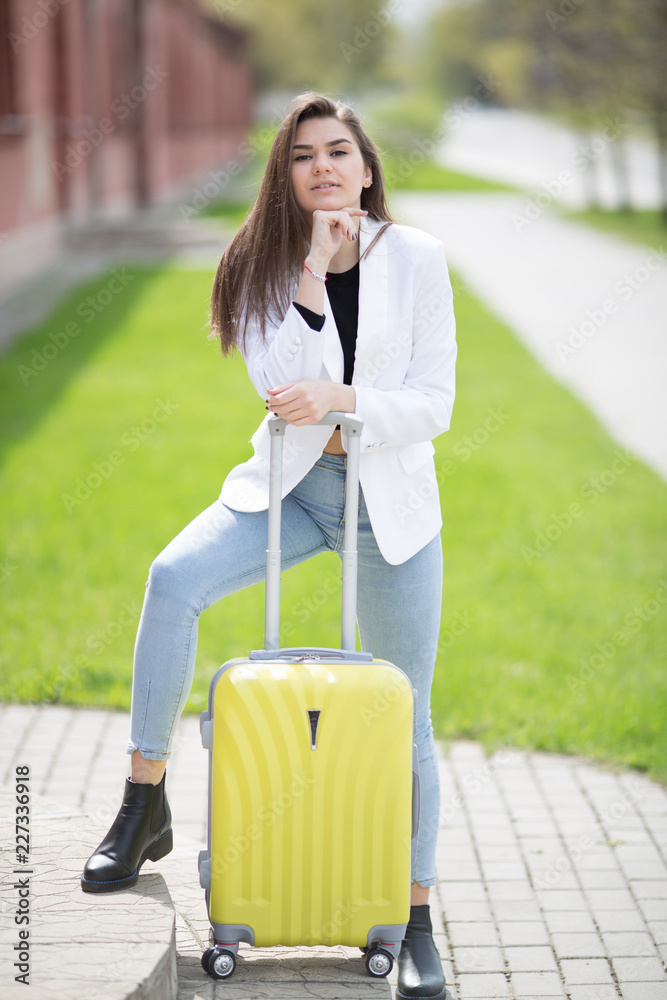 beautiful caucasian girl with long hair holding a big yellow suitcase. Concept - travel tourism