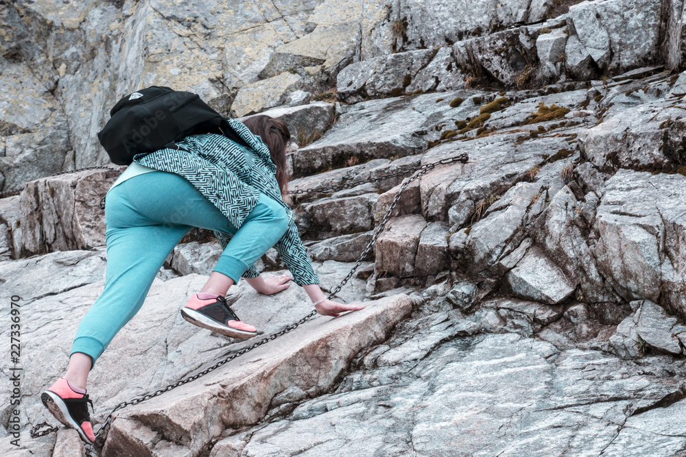 Young girl climbs the rocks on the mountain