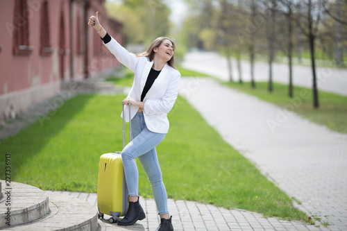 beautiful caucasian girl with long hair holding a big yellow suitcase. Concept - travel tourism