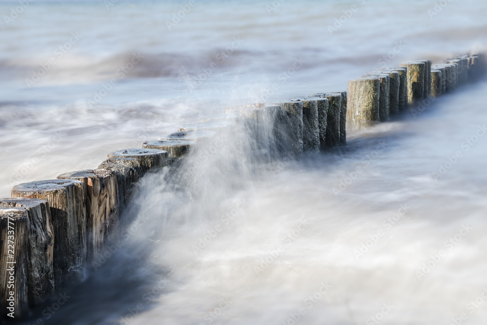 wooden groynes in the spray of the sea, smooth water by long exposure, nature background with copy space wooden groynes in the spray of the sea, smooth water by long exposure, nature background with copy space