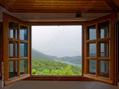 Fototapeta drewniana rama okienna z widokiem na górskie jezioro, mglista jesień
