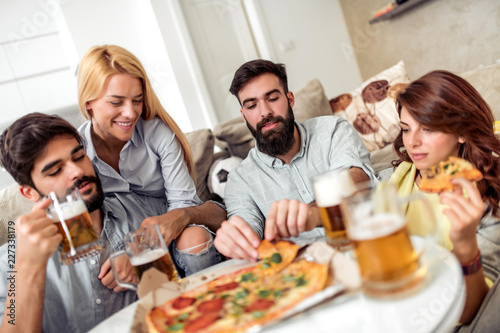 Group of friends enjoying pizza and beer