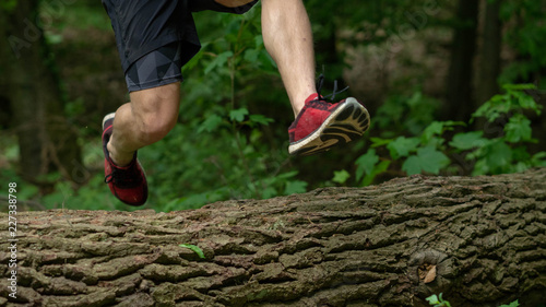 the guy jumps over a large log while participating in an ocr race photo