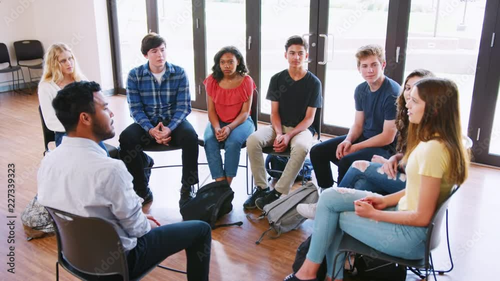Male Tutor Leading Discussion Group Amongst High School Pupils